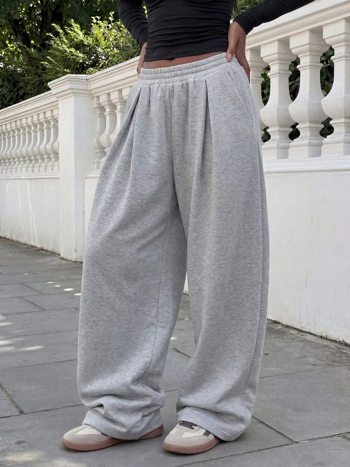 Angled front view of gray wide-leg sweatpants showing front pleats and the loose, full-length legs.